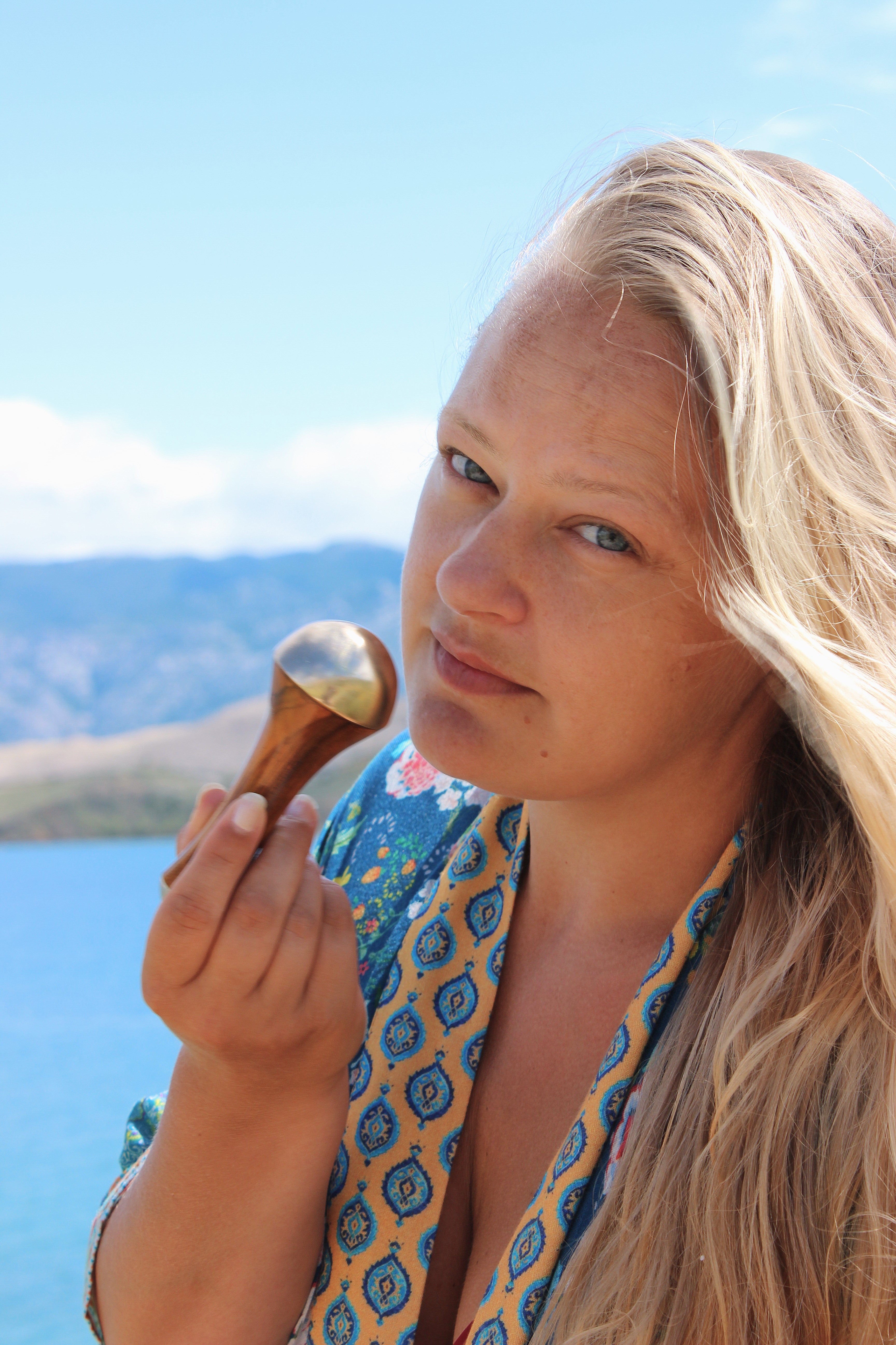 Woman using Art of Vedas Kansa Wand double sided for facial massage outdoors - Ayurvedic bronze face massage tool for skin rejuvenation