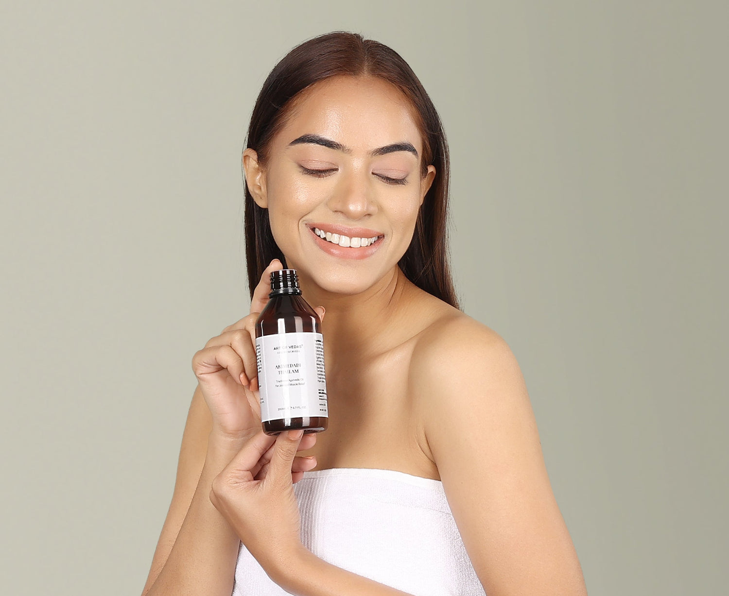 Woman holding Art of Vedas traditional Ayurvedic Thailam oil bottle - natural Ayurvedic skincare and wellness