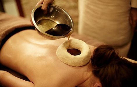 Kati Basti Ayurvedic lower back treatment explained by Art of Vedas - warm medicated oil poured into dough ring on spine for pain relief